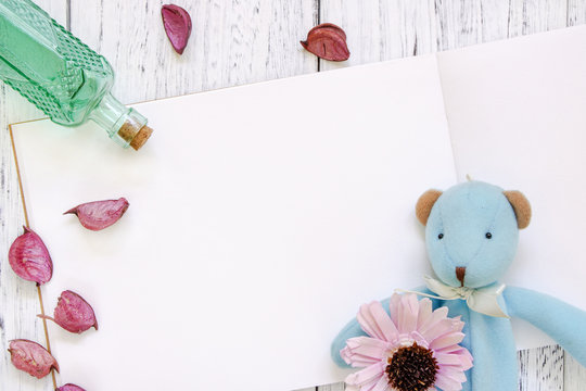 Stock Photography flat lay vintage white painted wood table purple flower petals bear doll green glass bottle