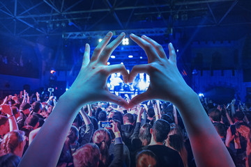 The silhouettes of concert crowd in front of bright stage lights