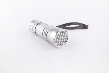 Silver LED flashlight on a white surface. Flashlight isolated on white background.