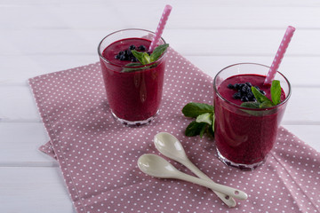 Blueberry smoothie with a straw and sprig of mint