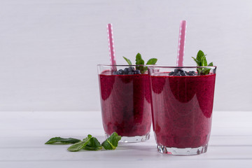 Two glasses of blueberry smoothie on white table