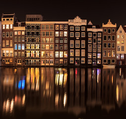 Beautiful traditional old buildings at night with reflection in Amsterdam, the Netherlands