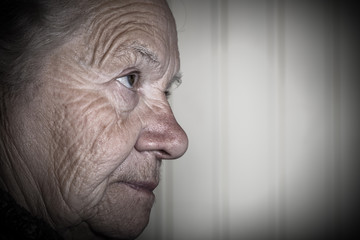 Portrait of an elderly woman on a light background. Thoughtful profile. Toned