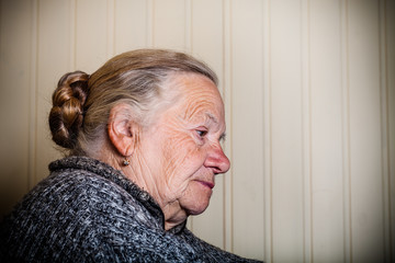 Portrait of an elderly woman on a light background. Thoughtful profile. Toned