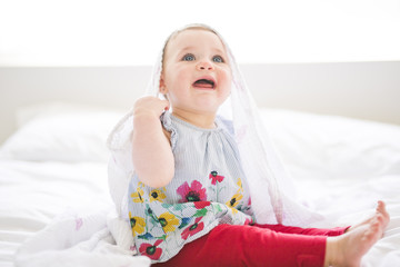 Portrait of a crawling baby on the bed in her room