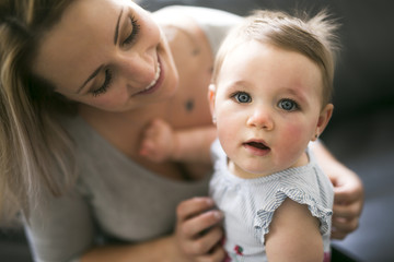Happy young mother with baby girl on sofa at home