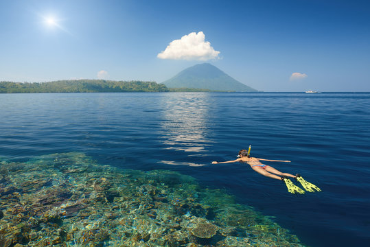 woman swimming in mask in clear tropical waters on a background of excotic islands