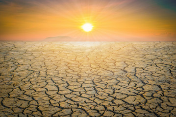 Dry cracked soil dirt or earth during drought at sunset.