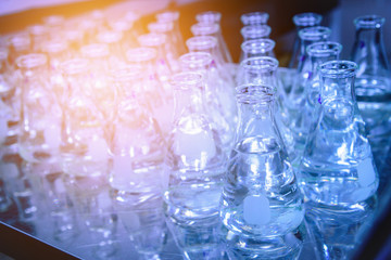 Glass flask with liquid in laboratory. Blue tone. Selective focus.