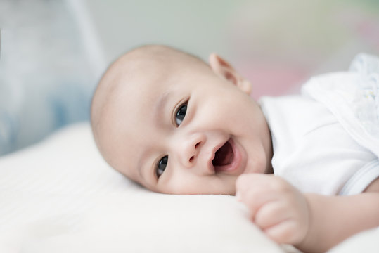 Portrait of cute 3 months Asian baby boy lying down on a blanket and smile.