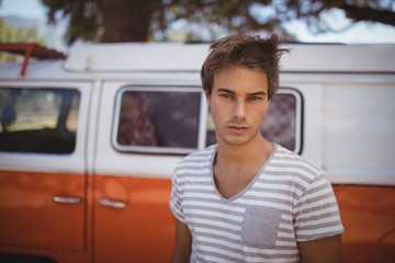 Portrait of young man standing against van