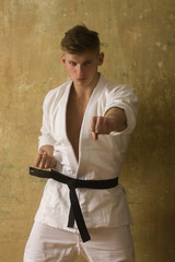 Naklejka na ściany i meble Strong fit athlete in white kimono with black belt