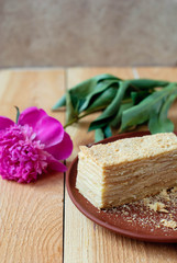 Fototapeta na wymiar Cake Napoleon on a wooden table with a peony flower.