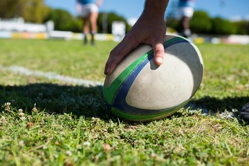 Cropped image of player touching rugby ball - obrazy, fototapety, plakaty