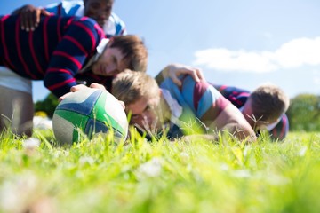 Close up of men playing rugby while lying at grassy field