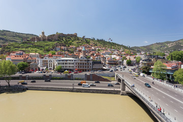 Fototapeta na wymiar Panorama view of Tbilisi, capital of Georgia country. Landmarks - Narikala fortress, cable road above tiled roofs, Meidan square.