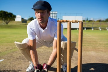 Wicket keeper crouching by stumps during match