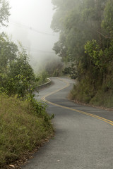 winding road with barrier in the mountains with fog in a cold winter day