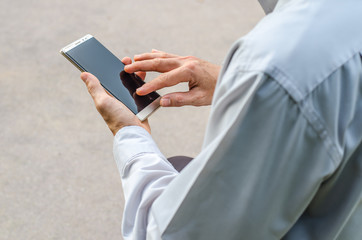 Man uses his Mobile Phone is outdoor park, close up