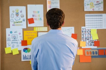 Male executive looking at the bulletin board in office