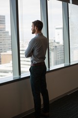 Fototapeta premium Male executive looking through window in office