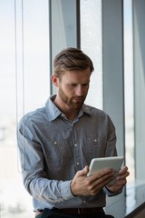 Male executive using digital tablet near window