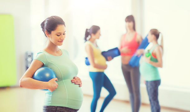 happy pregnant woman with ball in gym