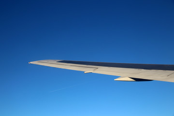 Fototapeta premium Passenger aircraft wing in flight against a blue sly