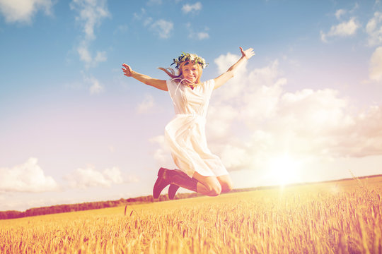 happy woman in wreath jumping on cereal field