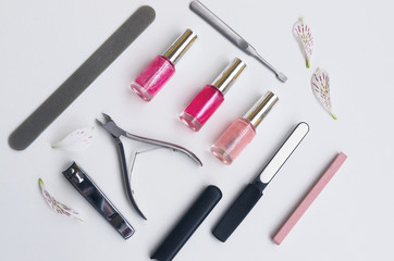 Obraz na płótnie Canvas Manicure and pedicure tools and accessories mostly used in beauty salons. diamond nail file, stone nail file cuticle remover, nail clipper and three nail polish in rose pink tone. 