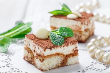 Mini cakes tiramisu with white chocolate, cocoa and candies on light background close up. Delicious dessert and candy bar