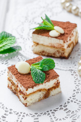 Mini cakes tiramisu with white chocolate, cocoa and candies on light background close up. Delicious dessert and candy bar