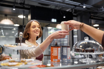 happy woman taking coffee cup from seller at cafe