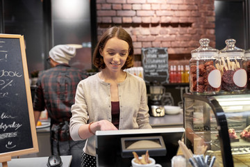 happy woman or barmaid with cashbox at cafe