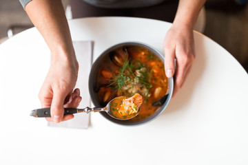 woman eating seafood soup at restaurant