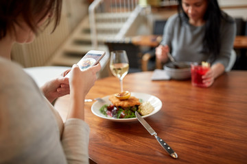 women with smartphones and food at restaurant