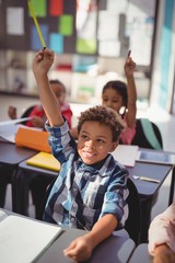 Schoolkids raising their hands in classroom