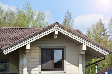 Part of the facade of a wooden house with windows and sun beams
