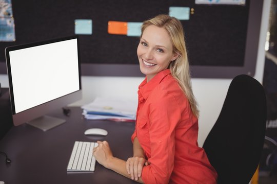 Portrait Of Smiling Teacher Sitting At Desk