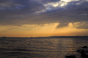 Empty cloudy sky from orange to blue with sun rays during the sunset