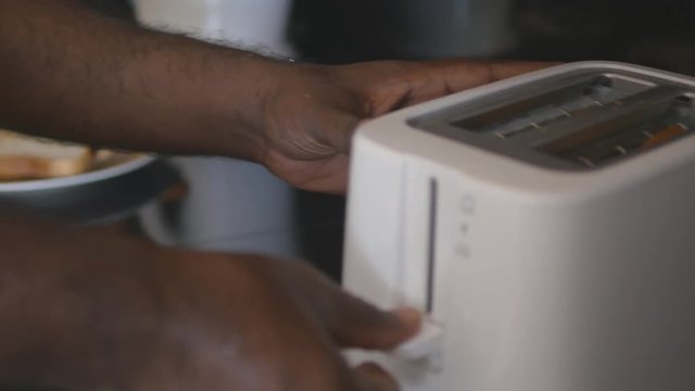 Male indian hands put in toaster two slices of bread, and then toasted. Close up