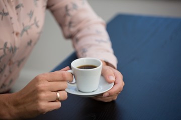 Businesswoman holding coffee cup and saucer in cafe