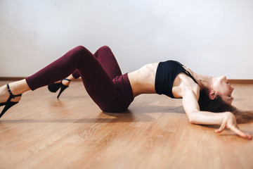 A young dancer practicing dance moves lying on her back in a dance class. Dance training