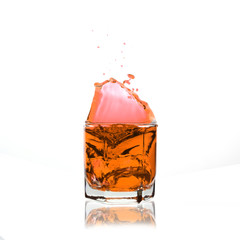 orange cocktail splashing on a glass on white background