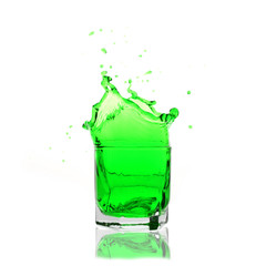 green cocktail splashing on a glass on white background