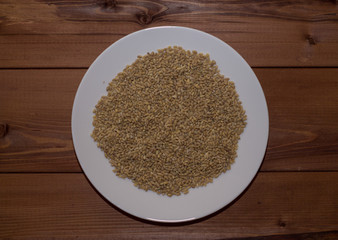 Pearl barley in a white plate. Wooden background