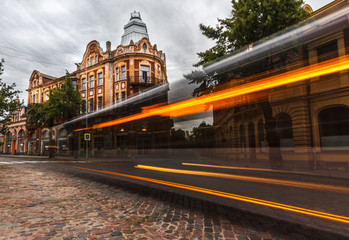 Long-exposure of bus passing by historical building.