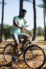 Naklejka premium Man with headphones riding bicycle in the park