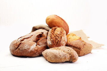 Different kinds of bread and bread rolls on board from above. Kitchen or bakery poster design.