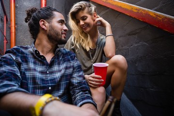 Romantic couple enjoying while having drink on staircase - Powered by Adobe